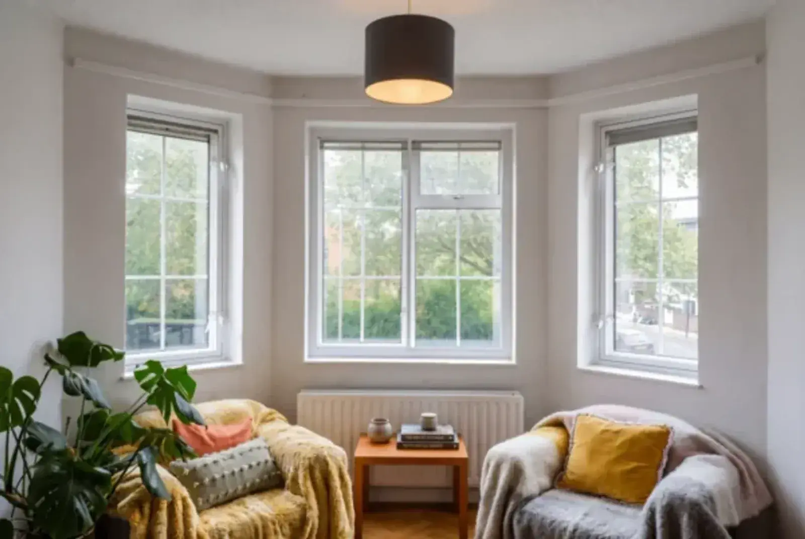 Bright sitting room with three white-framed windows and soft furnishings