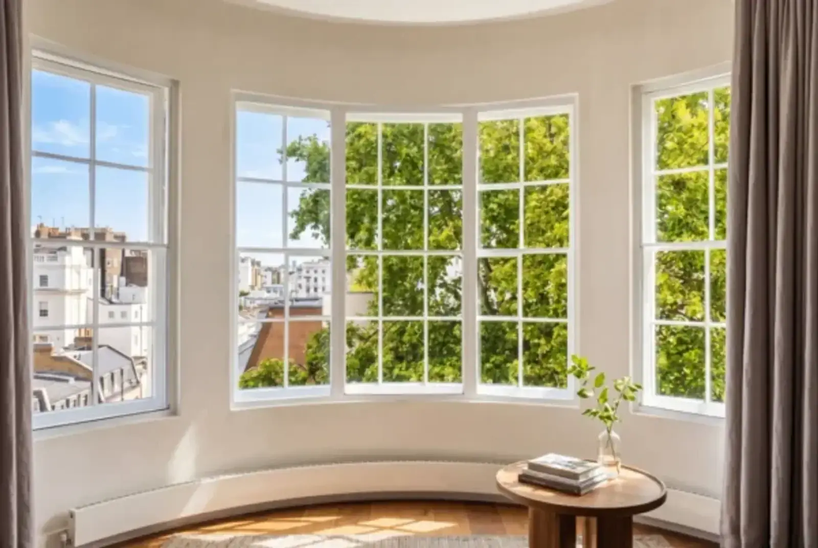 Sunlit curved bay window overlooking leafy trees and rooftops