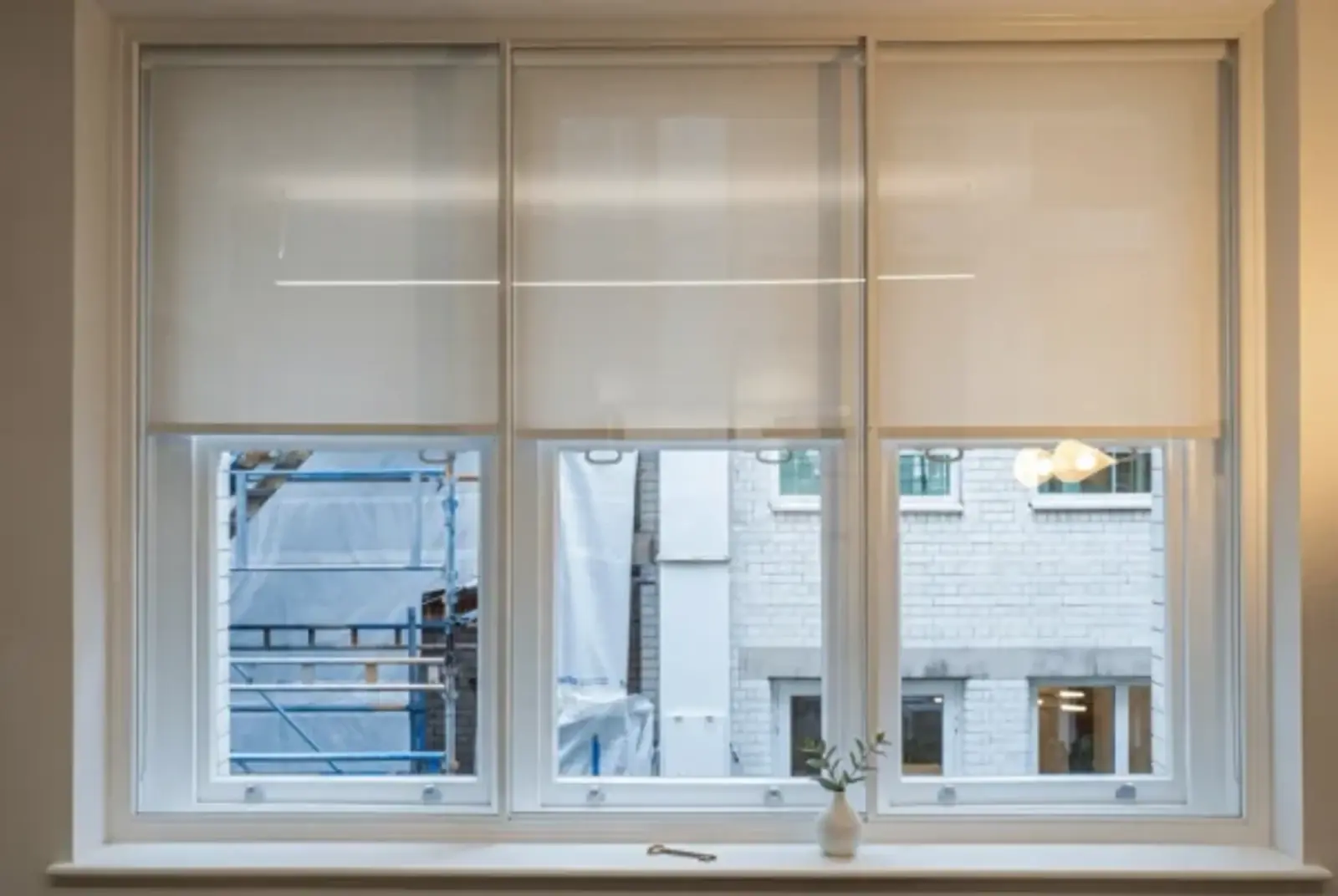 Wide interior window with slim white frames and roller blinds