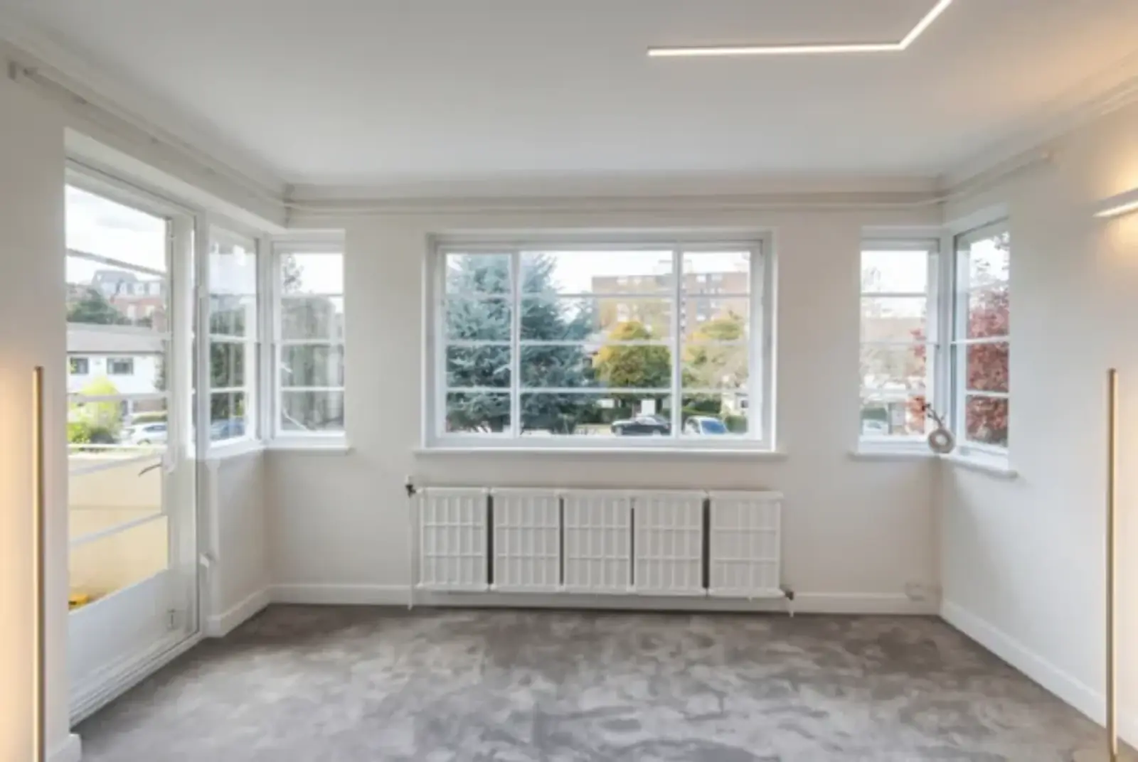 Bright empty sitting room with a wide bay window and radiator