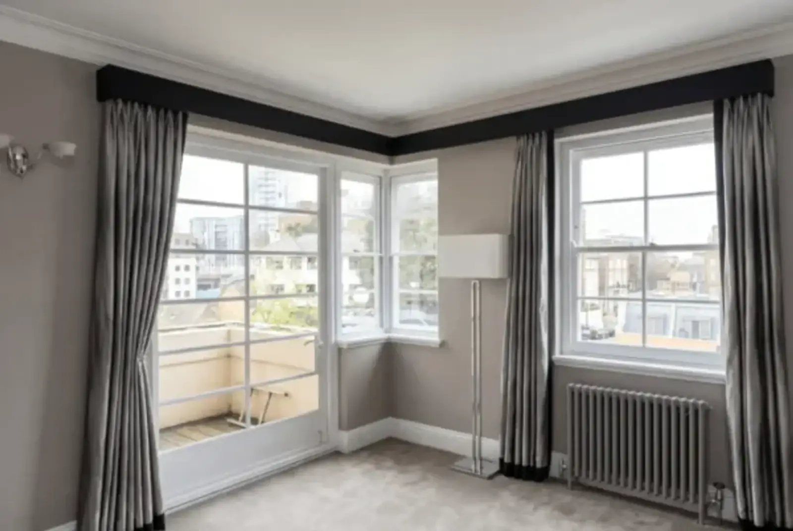 Quiet sitting room with curtained windows, a balcony door and radiator