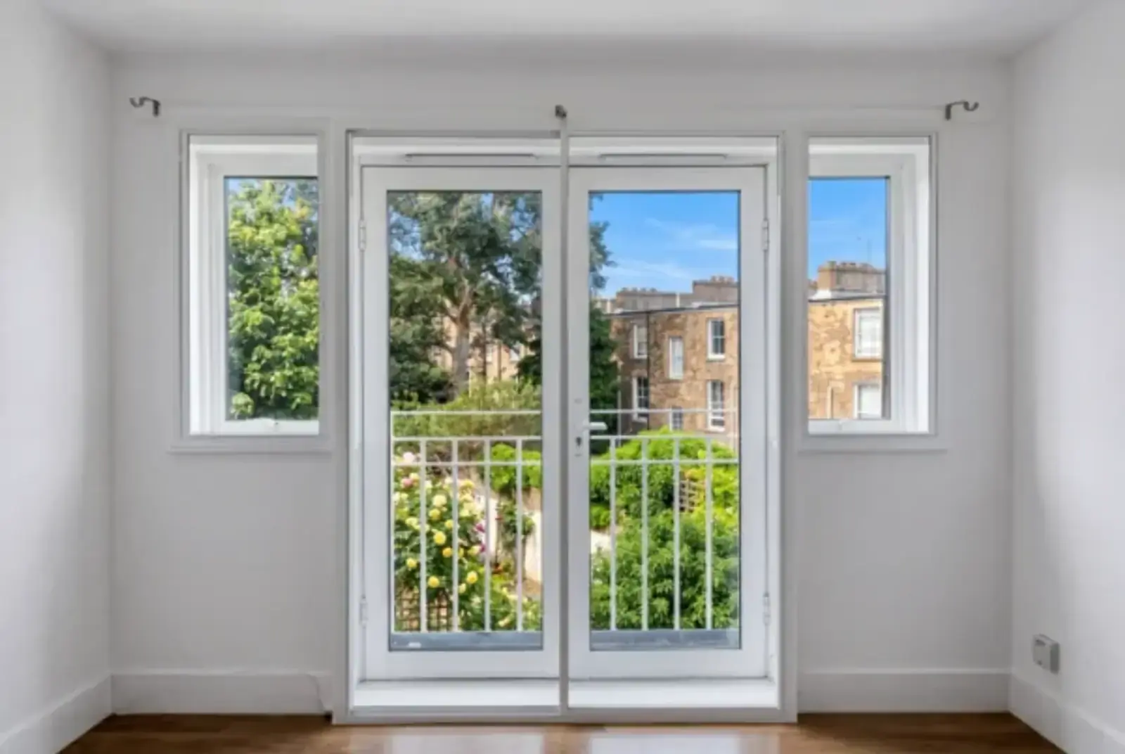 Bright room with white-framed French doors opening to a planted garden and period terraces