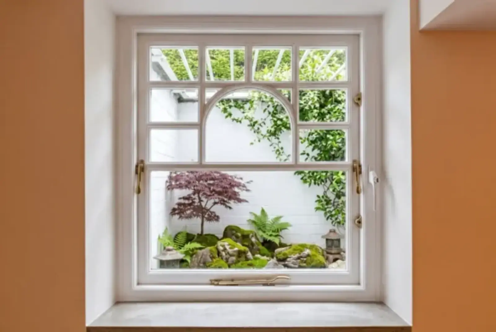 White-framed arched window looking onto a leafy courtyard garden