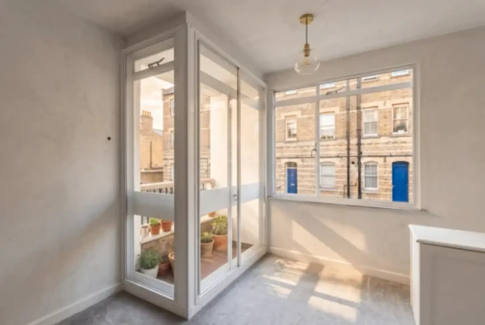 Sunlit room with secondary glazed balcony doors and a wide window overlooking terraced homes