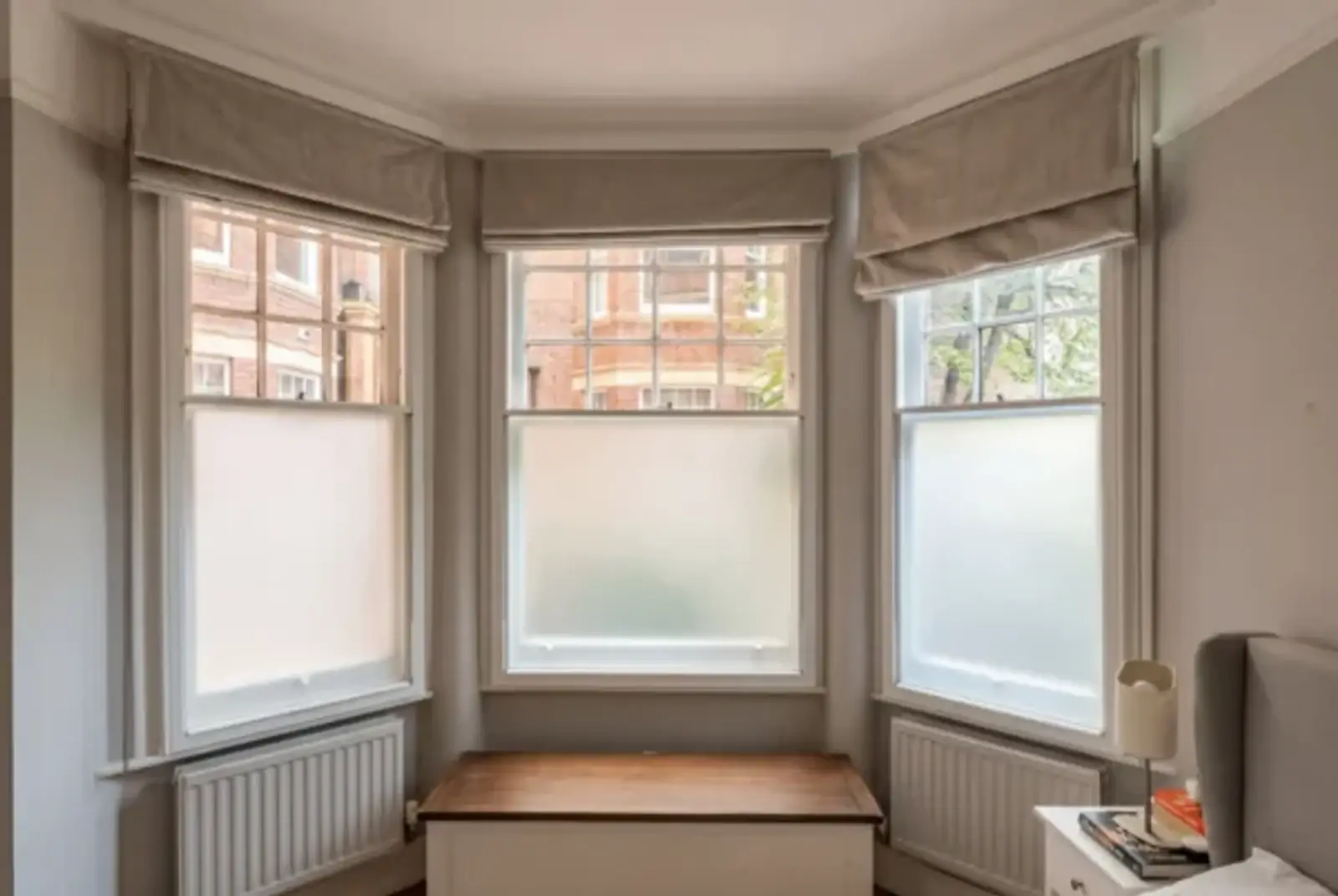 Bay window with roman blinds and frosted lower panes in a calm period room