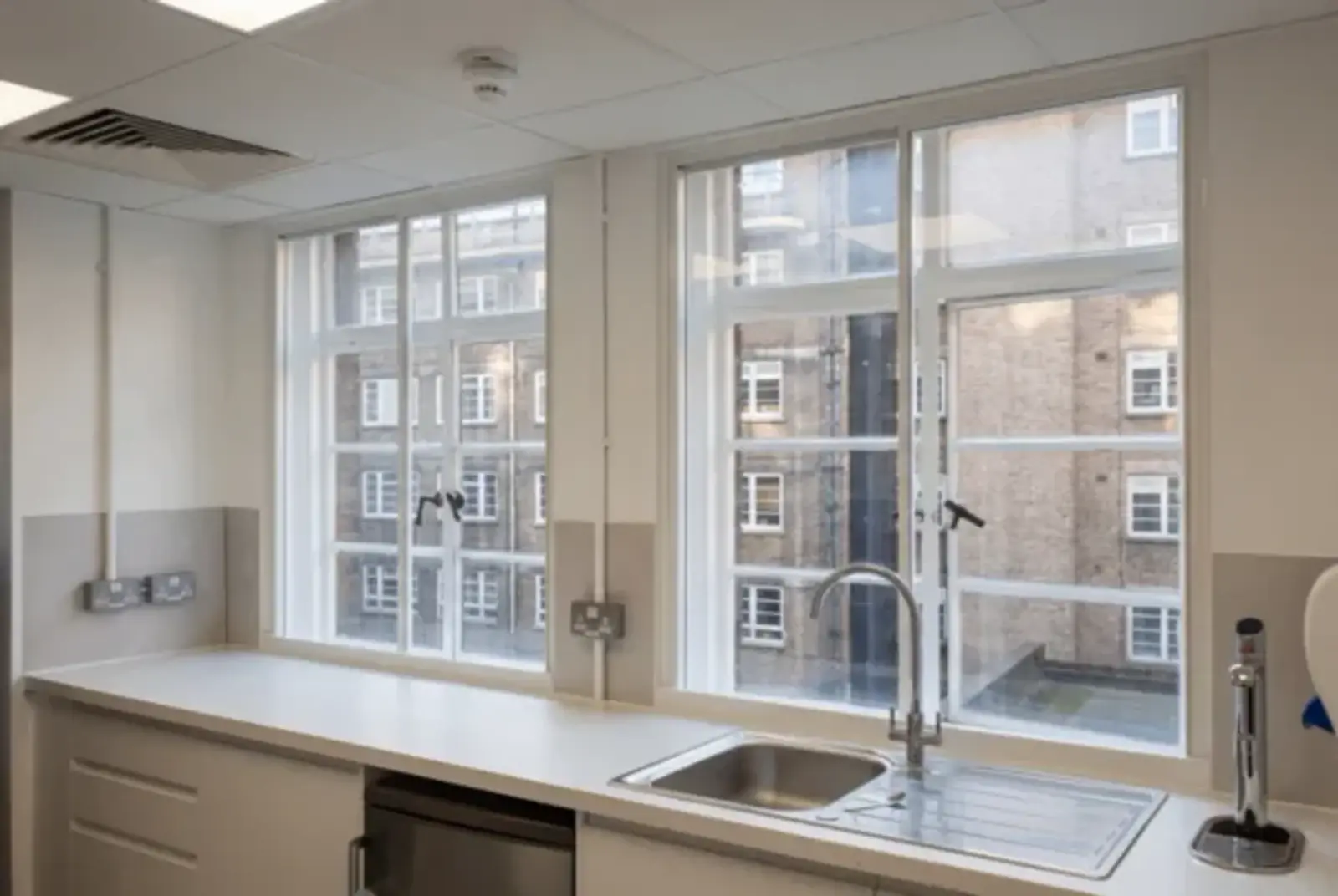 Bright kitchen with wide secondary glazed windows overlooking an inner-city courtyard