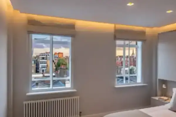 A peaceful bedroom at sunset with sash windows, illustrating the tranquil atmosphere achieved through professional soundproofing.